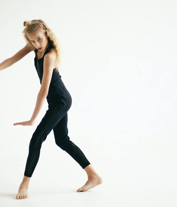 Woman performing a fluid, energetic movement in a minimalist studio.